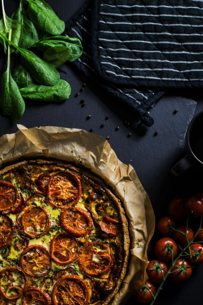 A delicious homemade tomato quiche with fresh spinach, ready to serve, perfect for dinner.